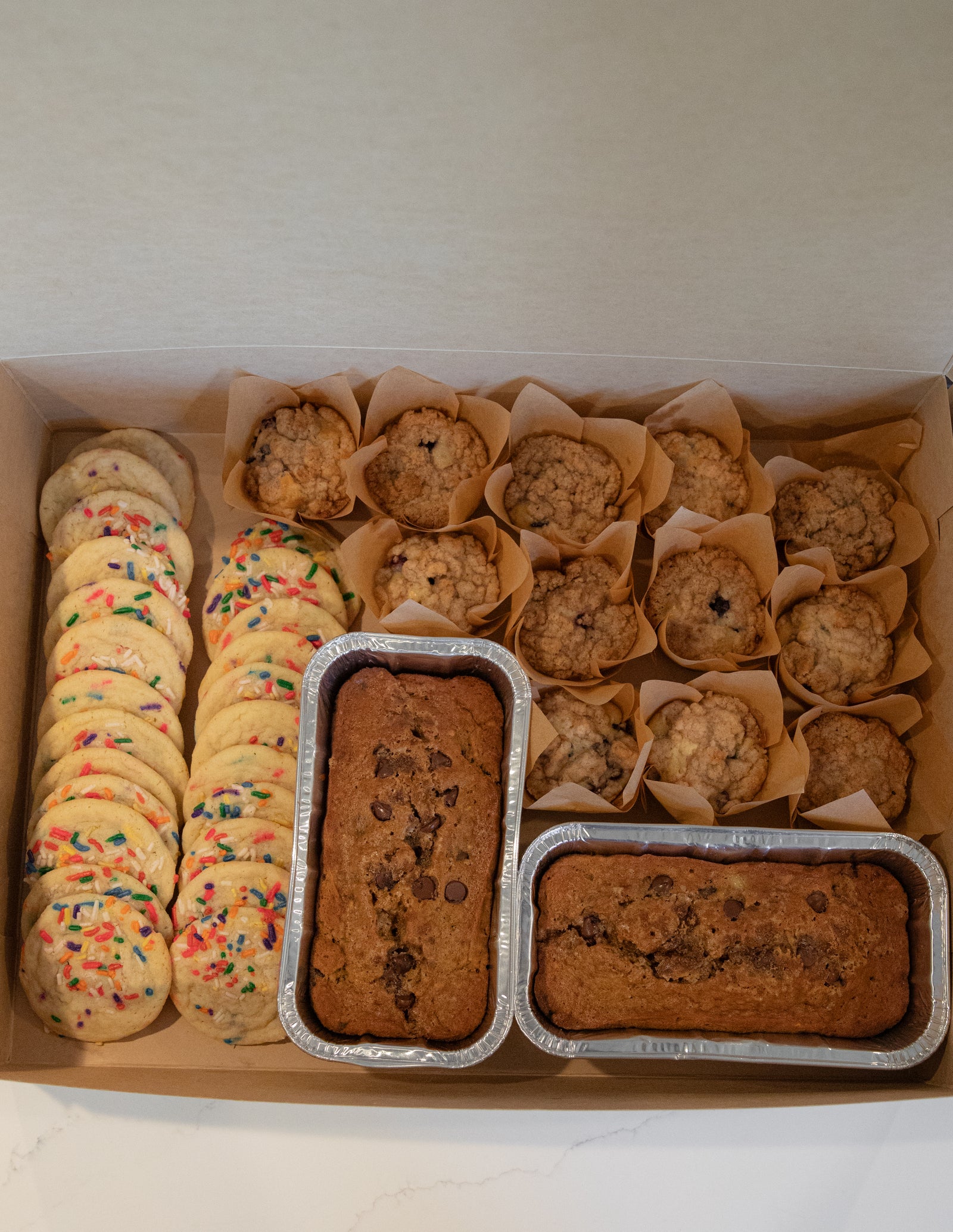A large Bliss Bakery box filled with cookies, muffins and specialty loaves